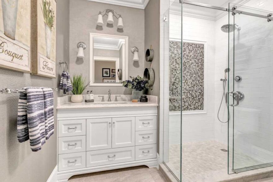 white bathroom vanity with silver hardware, walk in shower with silver shower fixtures
