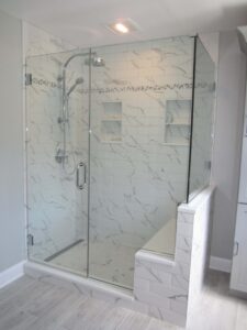 walk in shower with white marbled shower tile with silver showerhead