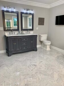 white marbled herringbone bathroom floor tile with dark grey vanity with silver hardware