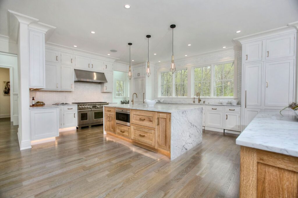 white kitchen cabinets, wooden kitchen island with white marble countertop, gold kitchen fixtures