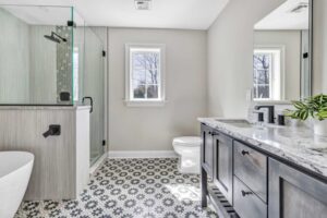 bathroom with gray vanity, white toilet and bathtub, black shower fixtures, black floral floor tile
