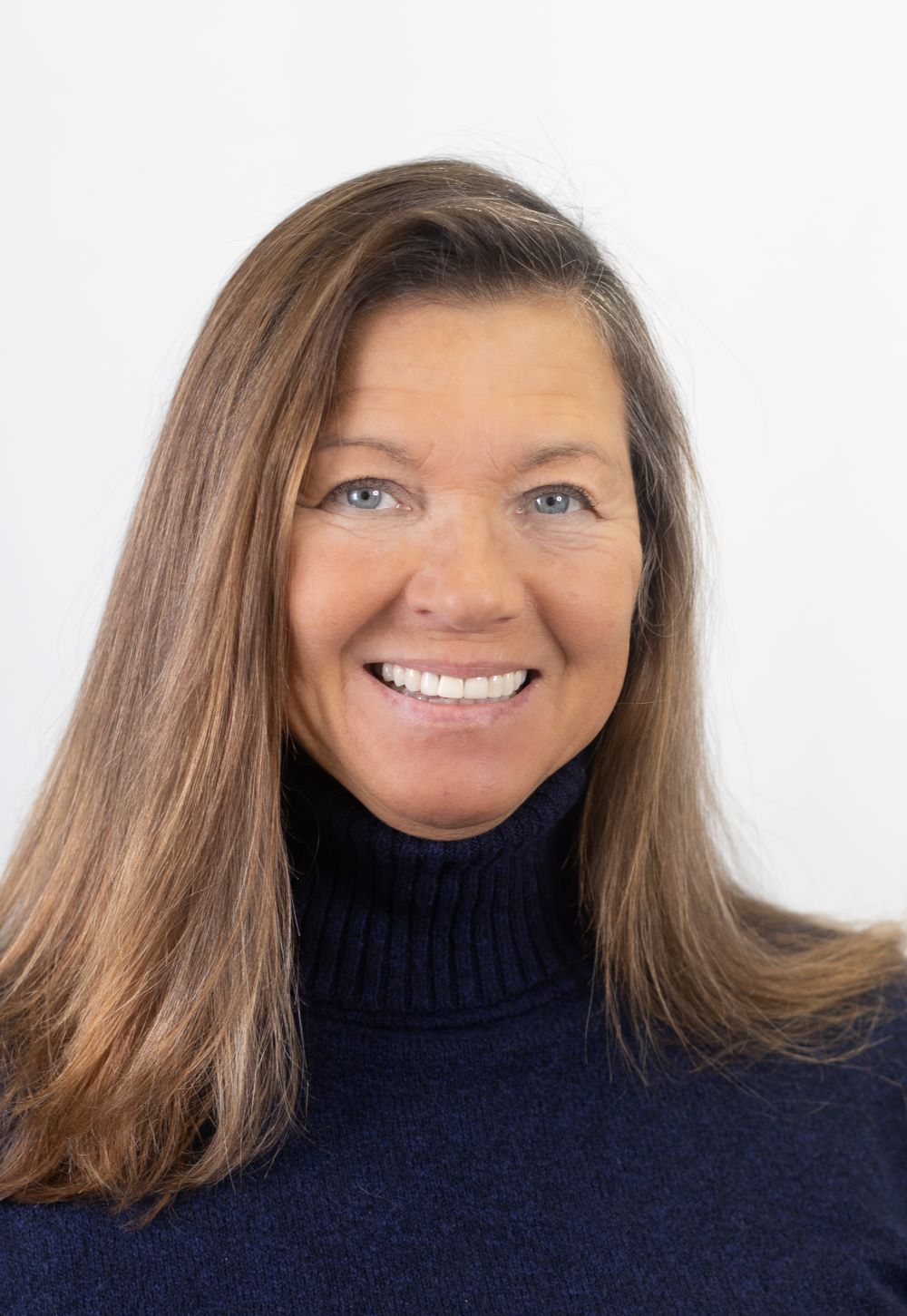 A smiling saleswoman with brown hair and a navy blue turtleneck sweater
