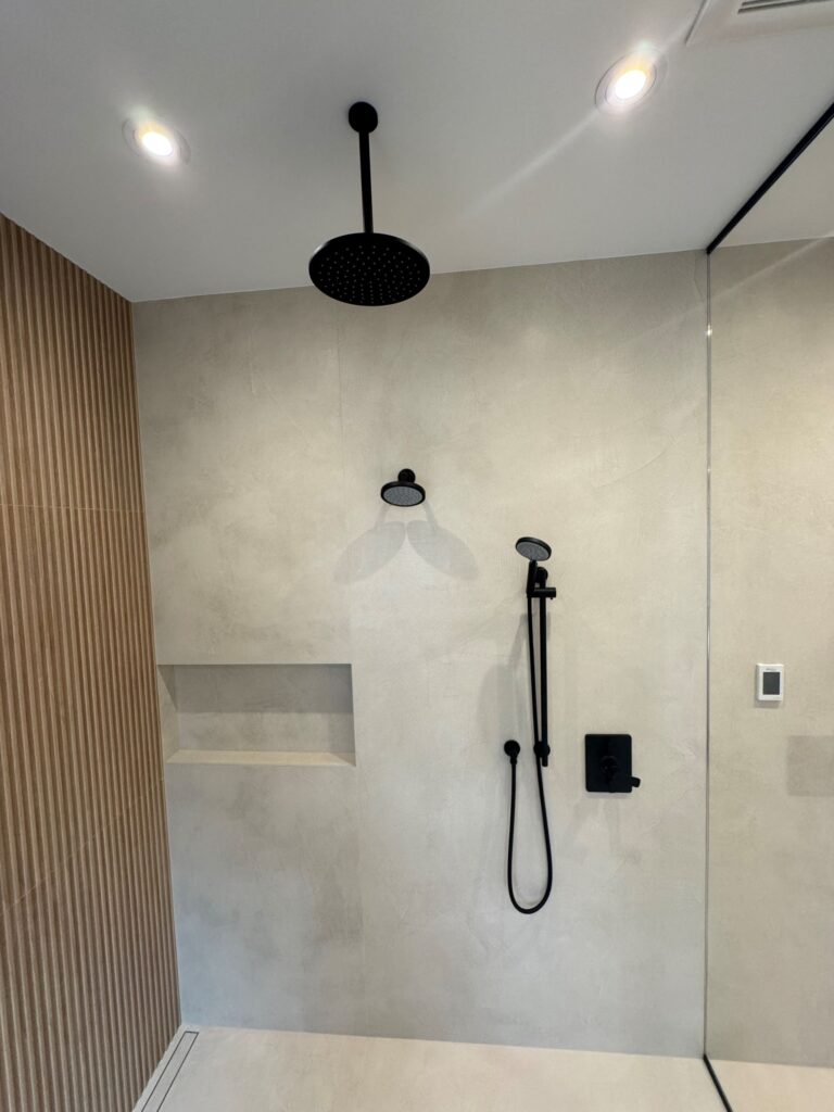 shower with white tile, black fixtures and wood accents