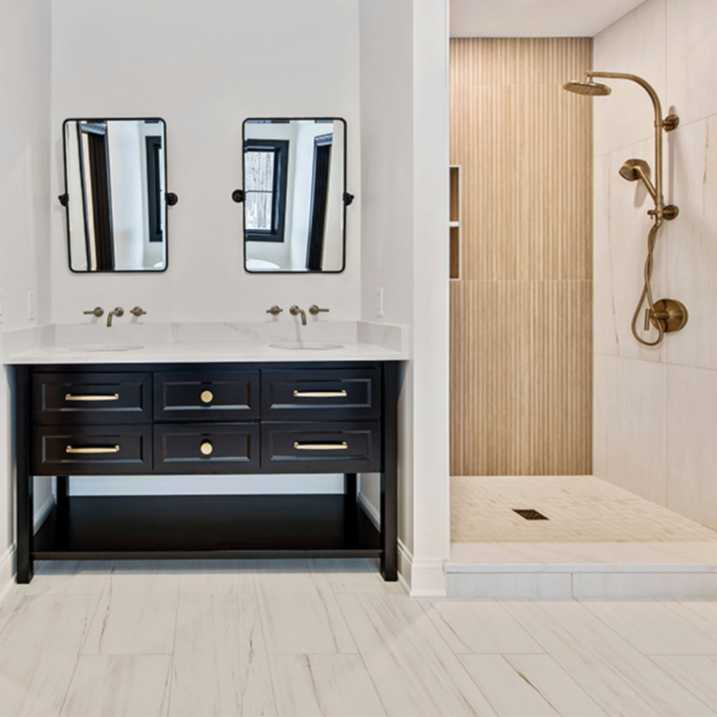 black vanity with wood panel shower and brushed bronze fixtures