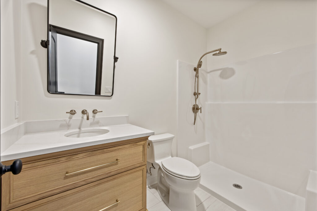 white walk in shower, white oak bathroom vanity, brushed bronze plumbing fixtures