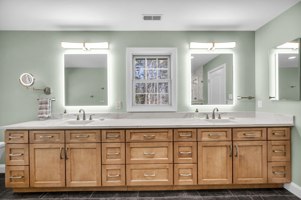 large wood vanity with white counter tops and illuminated mirros